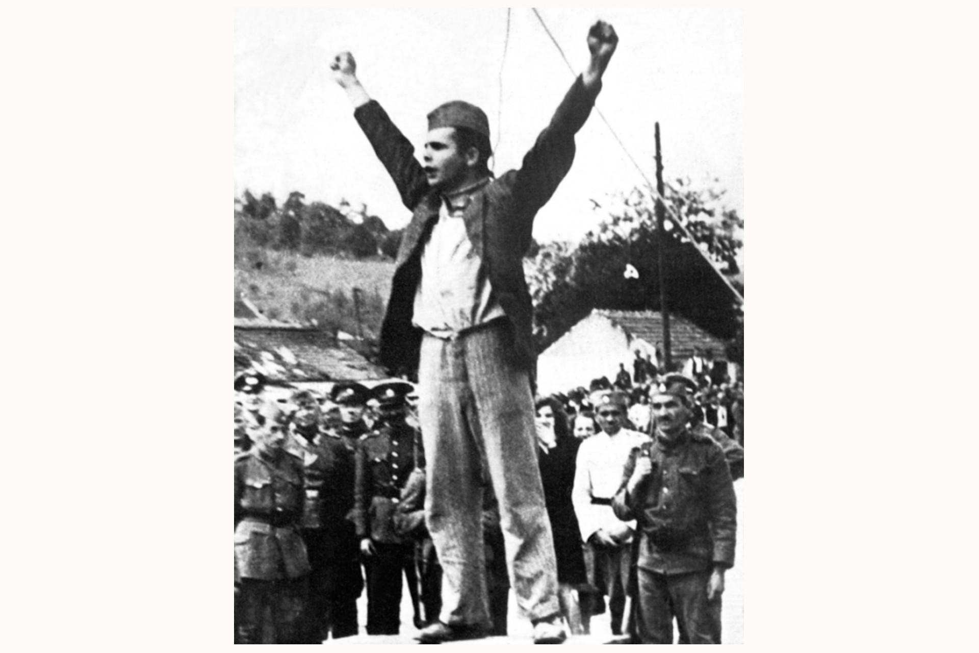 Der Nationalheld Stjepan Filipović kurz vor seiner Erhängung am 22. Mai 1942. Fotografiert von Slobodanka Vasić. (Mit freundlicher Genehmigung von Valjevo.znaci.net). Dieses Foto von Stjepan Filipović – oder Stevan Kolubarac, wie er in Serbien genannt wurde – war eines der Partisanenfotos, die außerhalb der Grenzen Jugoslawiens am weitesten verbreiteten wurden. Filipović war vor dem Krieg Gewerkschafter gewesen und schloss sich zu Beginn des Volksaufstandes den Partisanen an, zunächst als stellvertretender Kommandant der Kolubara-Kompanie und dann als politischer Kommissar des Macvan-Kommandos. Nach seiner Gefangennahme übergaben ihn die serbisch-nationalistischen Tschetniks den deutschen Truppen, die ihn als Warnung an andere Widerstandskämpfer öffentlich im Zentrum von Valjevo erhängten. Dieses Foto des 26-jährigen Filipović unter dem Galgen mit einer Schlinge um den Hals und erhobenen Armen wurde nur wenige Minuten vor seiner Hinrichtung aufgenommen. Als er auf dem zentralen Platz der Stadt vor etwa 3.000 Menschen stand, gab er sich nicht gedemütigt, sondern wiederständig. Er wandte sich mit folgenden Worten an die Menge: »Schaut nicht nur zu, schlagt die Bastarde. Zieht eure rostigen Gewehre. Wenn ihr nur zuschaut, werden uns die Bastarde einen nach dem anderen töten.«
