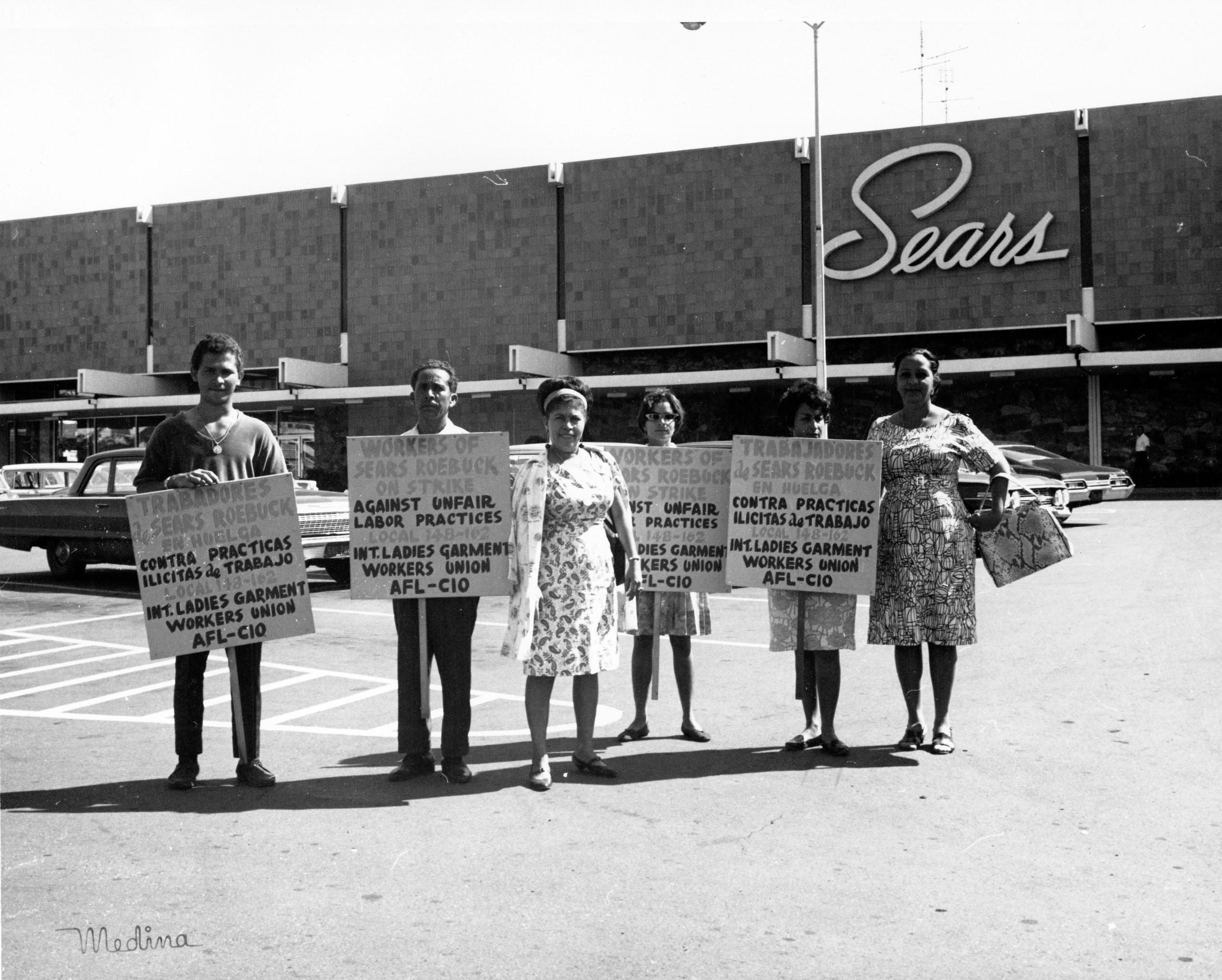Streikposten der International Ladies' Garment Workers' Union (ILGWU) geben auf Englisch und Spanisch ihren Streik gegen Sears Roebuck bekannt, Februar 1965.