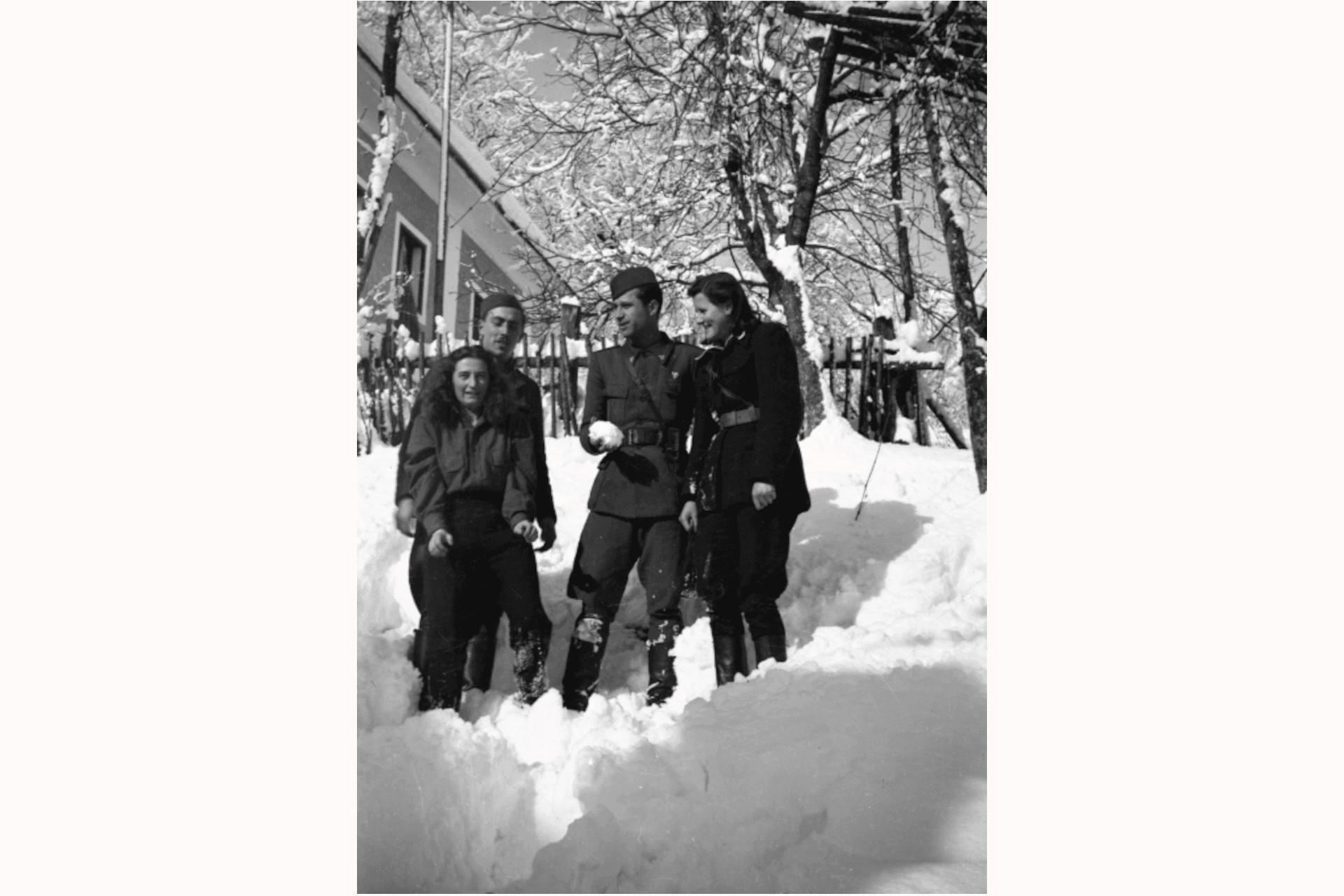 Winter, im Schnee. 21. Januar, 1945, Poljane, Kroation. Fotografiert von Aleksander Jesenovec. (Mit freundlicher Genehmigung des Museums der Zeitgeschichte Sloweniens, Ljubljana, Slowenien, SJ2/6; aus Formatierungsgründen beschnitten). Von links nach rechts: Iva Valenti, Verwalterin der Operation des Neunten Korps; Stanko Gorjanc, Leiter der Geodätischen Abteilung; Leutnant Mitar Raičević; und ein Partisan, der eine Zeit lang die Verwaltung der Operation des Neunten Korps übernahm und später Grundschullehrer wurde. Im Hintergrund ist das Haus zu sehen, in dem sich während des Zweiten Weltkriegs das Hauptquartier des Neunten Korps befand. Einige der Fotografien des Partisanenlebens lassen eine Normalität erkennen, die scheinbar im Widerspruch zu den Kriegsbedingungen steht, ganz so, als würden sie sich den Schrecken des Krieges verweigern. Oftmals sehen wir entspannte und lächelnde Gesichter, in denen sich die Freude über den ersten Schnee oder die Möglichkeit schwimmen zu gehen, spiegelt. Ihre Körperhaltung ist trotz der Militäruniformen häufig entspannt und individuell statt uniform. Fotografien dieser Art sind auch deshalb so wertvoll, weil sie uns einen direkten Einblick in die Lebensweise der temporären Gemeinschaften eröffnen, die sich in den befreiten Gebieten bildeten.