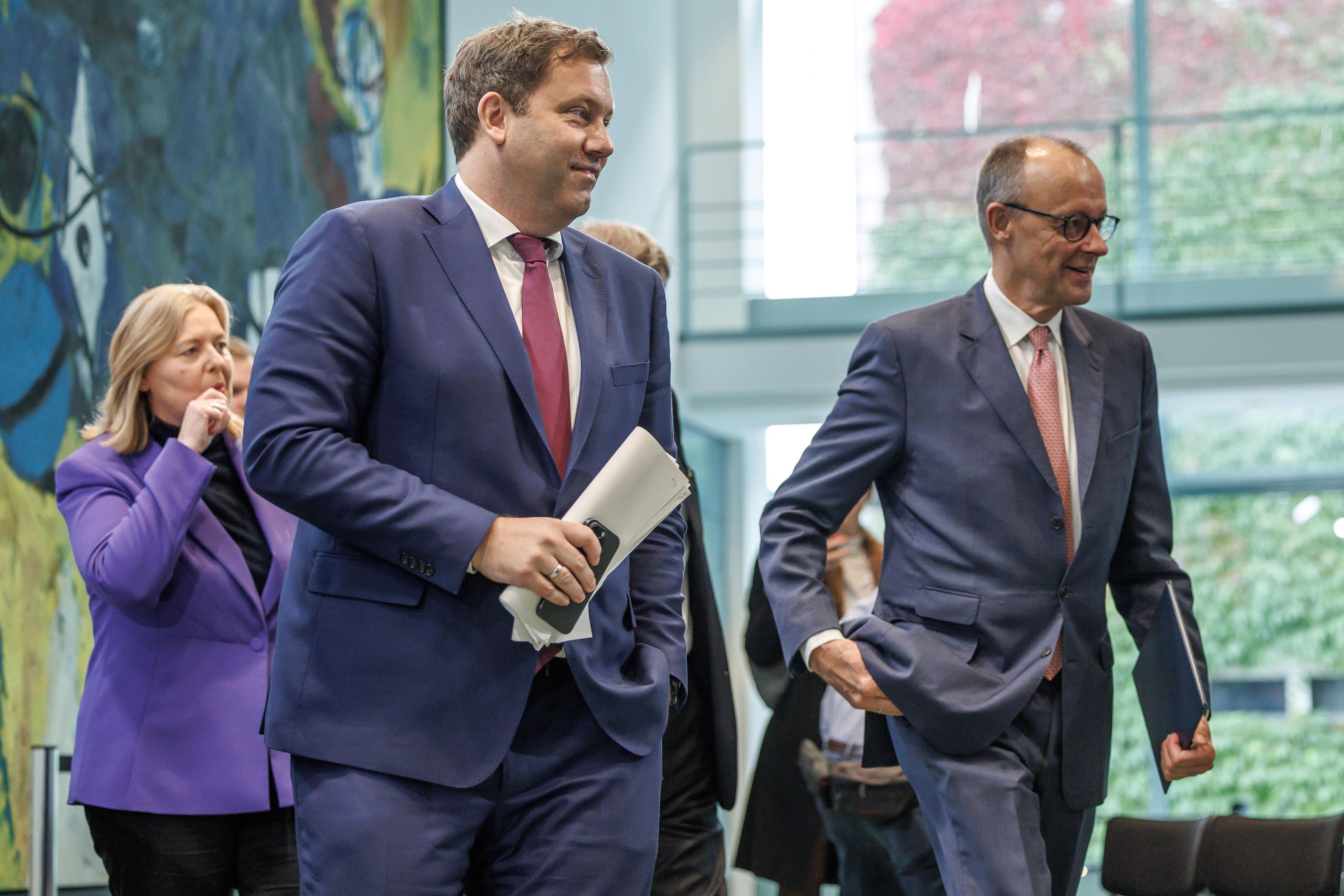 Friedrich Merz, Lars Klingbeil und Bärbel Bas schreiten beschwingt zur Pressekonferenz nach ihrem Koalitionsausschuss, um neue Härten für die weniger Privilegierten zu verkünden.