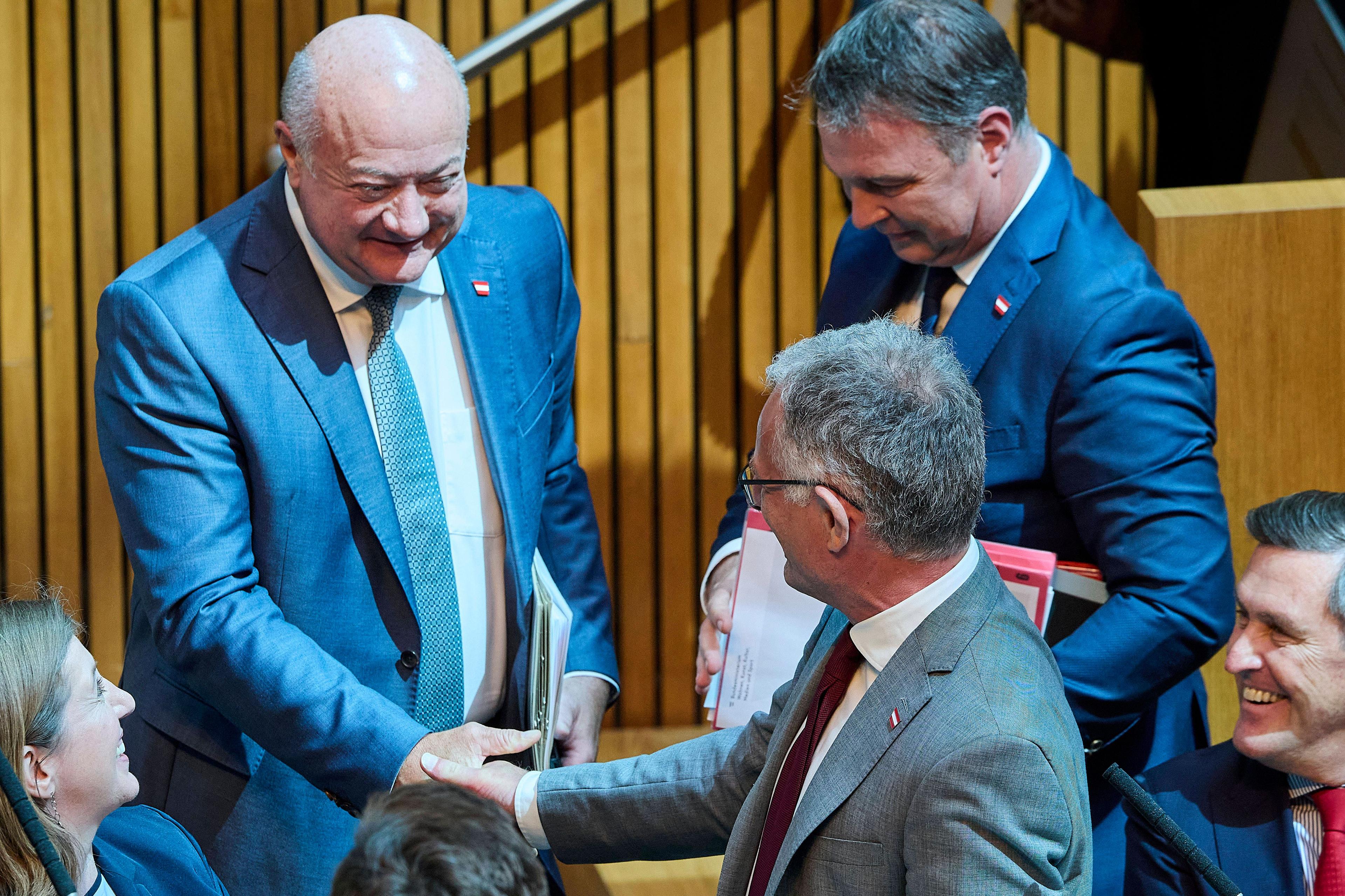ÖVP-Bundeskanzler Christian Stocker und SPÖ-Finanzminister Markus Marterbauer reichen sich die Hand, im Hintergrund SPÖ-Vizekanzler Andreas Babler.