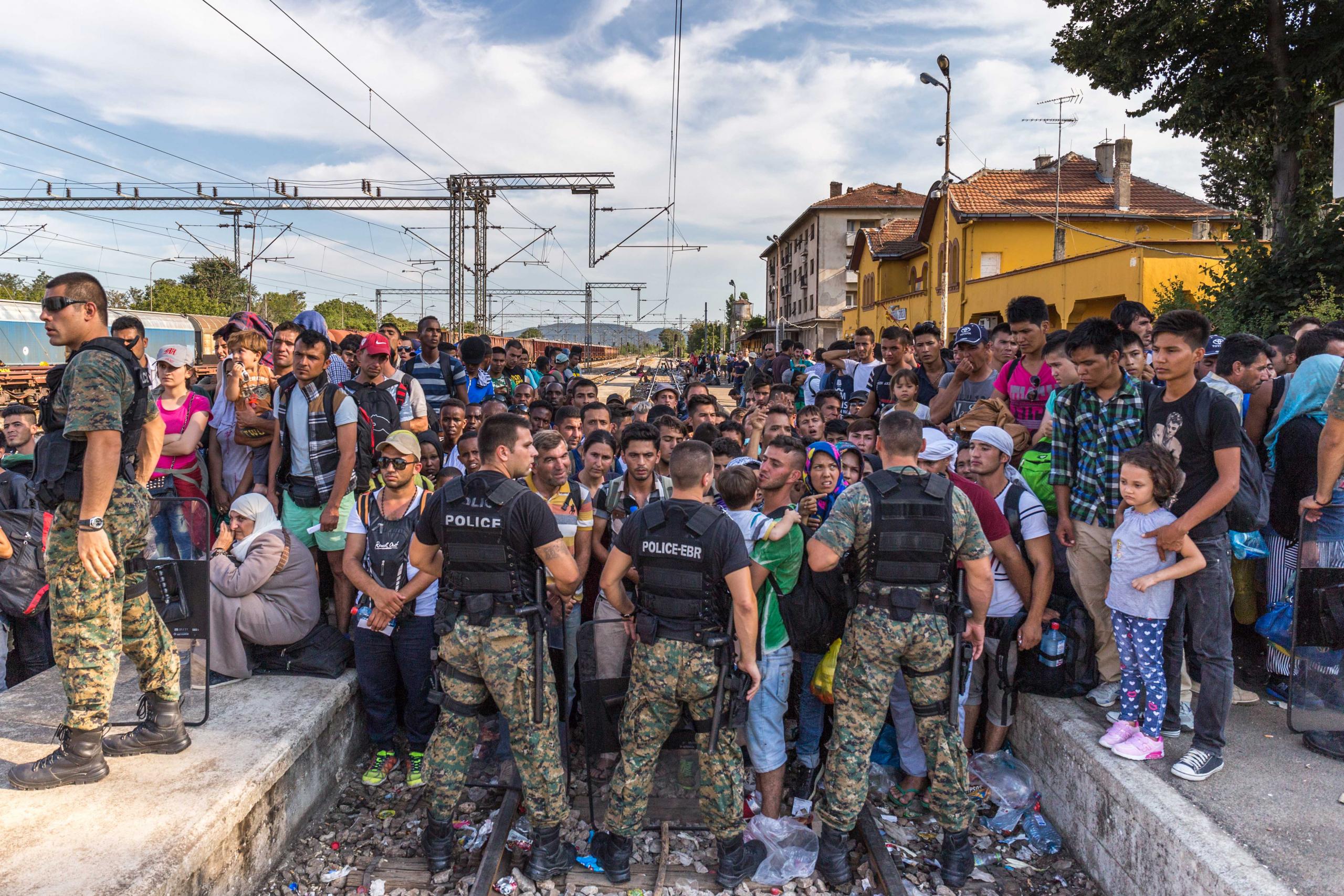 Nordmazedonische Grenzbeamte, die 2015, vor Schließung der Balkanroute, den Zugang zu Zügen in Richtung Westeuropa organisieren.