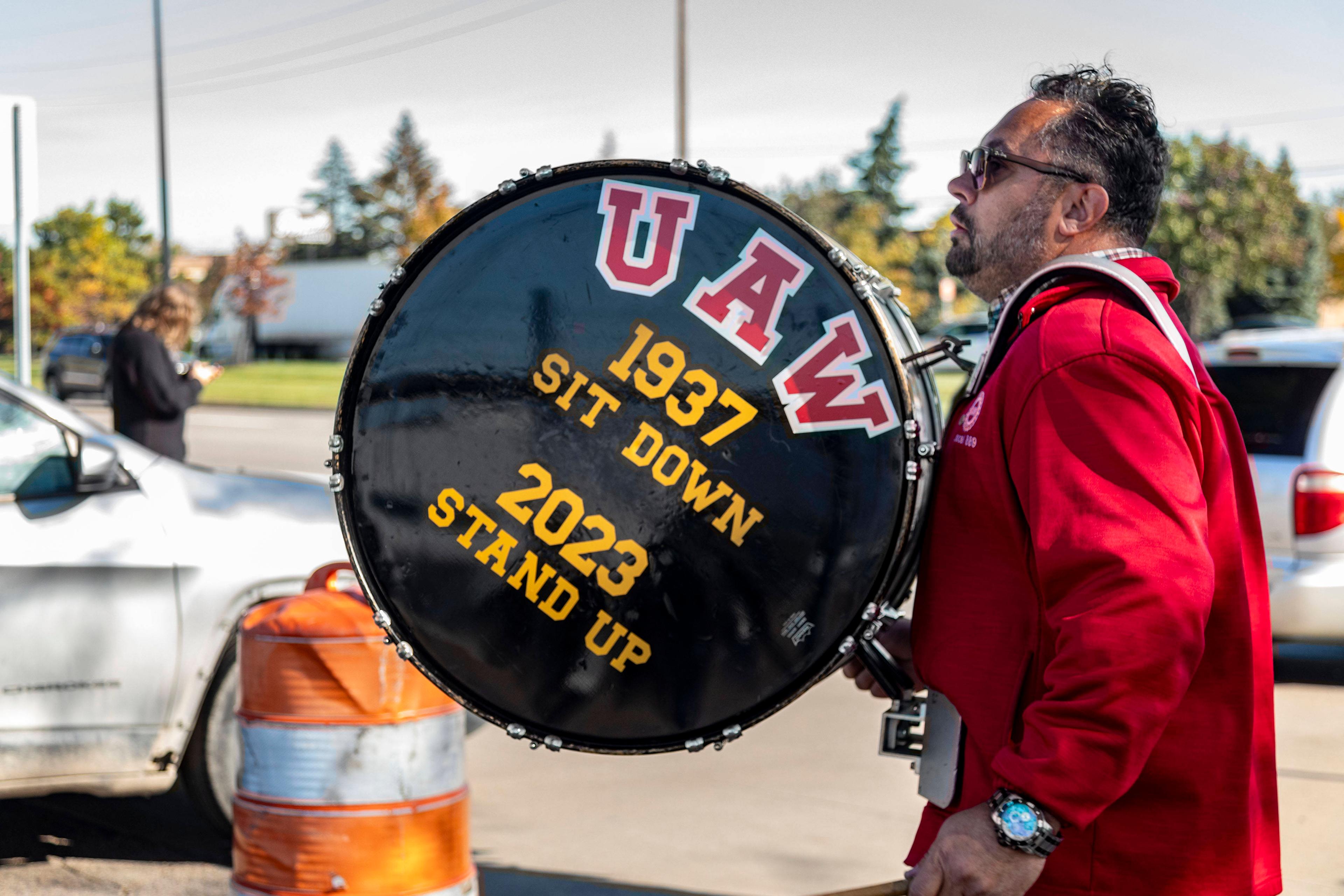 Ein Mitglied der United Auto Workers bei Stellantis trägt eine Trommel, auf der ein Vergleich zwischen dem historischen Sitzstreik von 1937 und dem derzeitigen Arbeitskampf gezogen wird, 23. Oktober 2023.