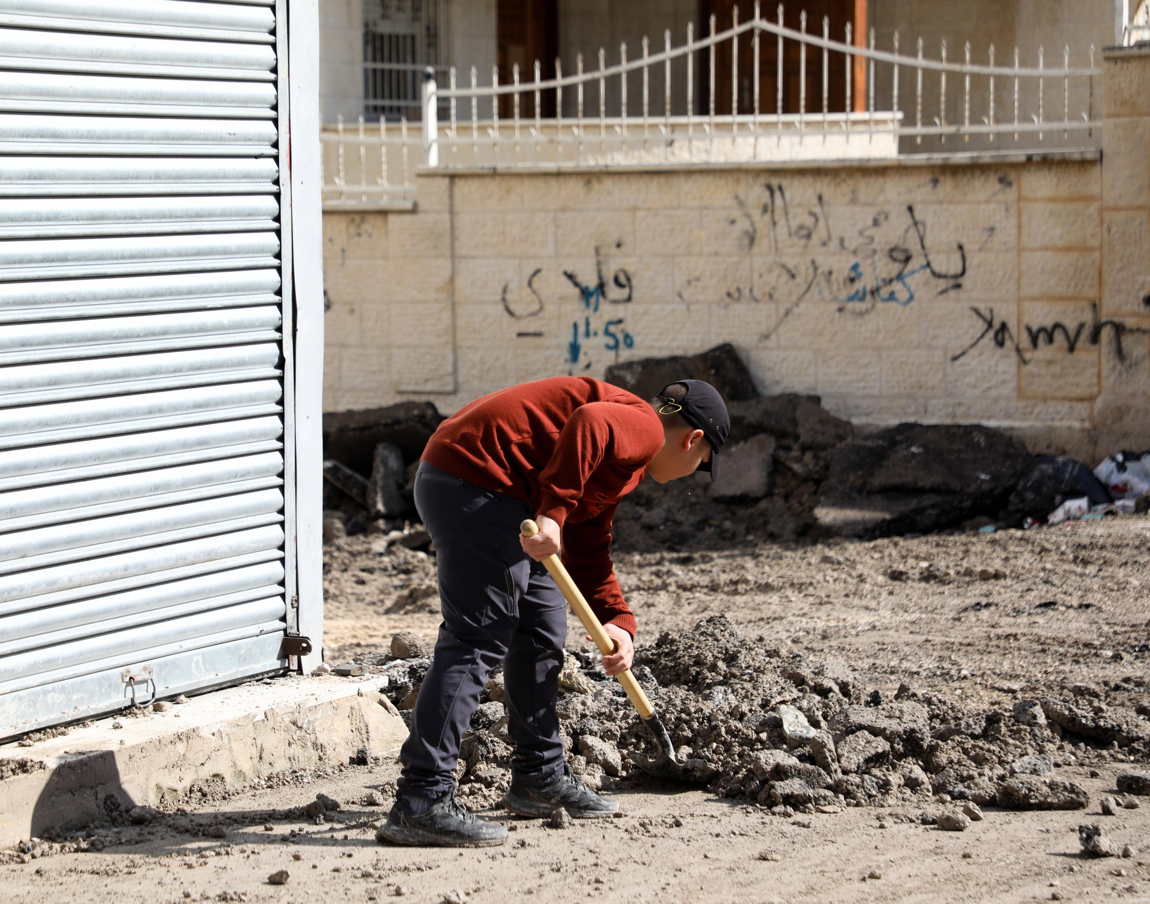 Ein Kind räumt nach israelischen Angriffen in Dschenin die Trümmer von der Straße.